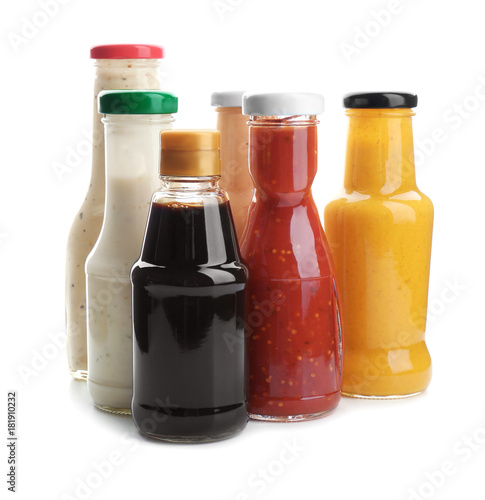 Bottles with different sauces for salad on white background photo