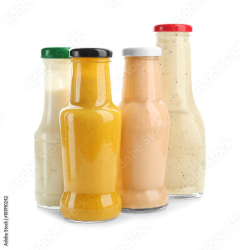 Bottles with different sauces for salad on white background
