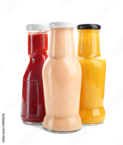 Photo Bottles with different sauces for salad on white background
