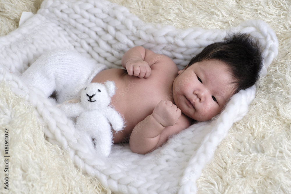 Portrait of Asia boy newborn is lay down on white fur background with bear . Portrait of Asia boy newborn is lay down on white fur background with bear .