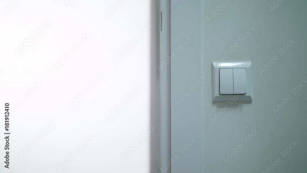 A hand switching on the light in a dark room. Close-up shot