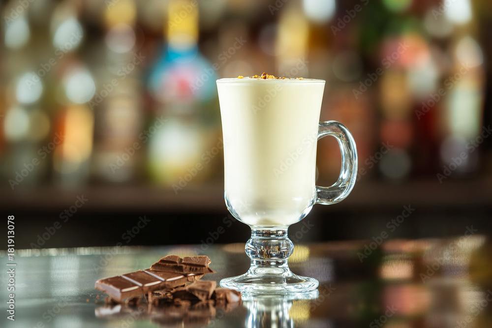 Glass of milk cocktail decorated with chocolate at bar counter background.