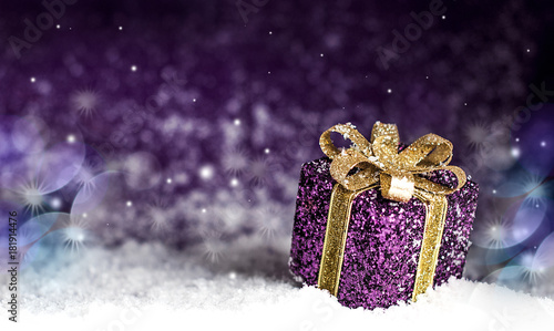 purple shiny gift with a gold bow, on a snowy background