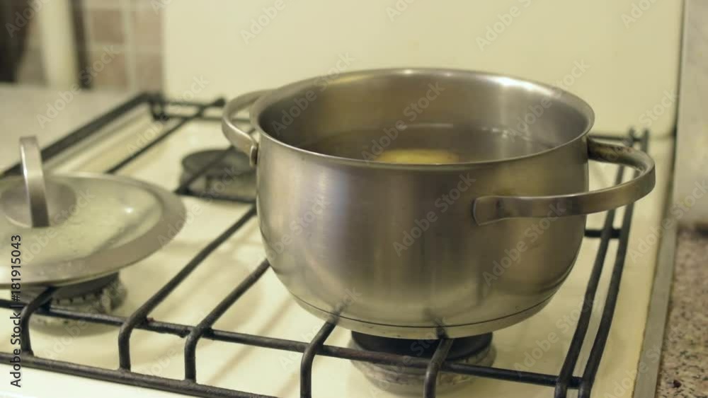 Boiling water at pan on gas stove top panel, close up