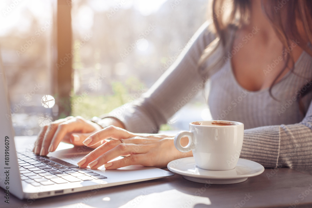 A girl is working at a laptop in a cafe on a sunny day A girl is working at a laptop in a cafe on a sunny day
