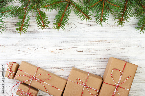 Pretty Christmas holiday border with decorative gifts tied with red ribbon and bows on fresh pine branches on a rustic wooden background with copyspace photo