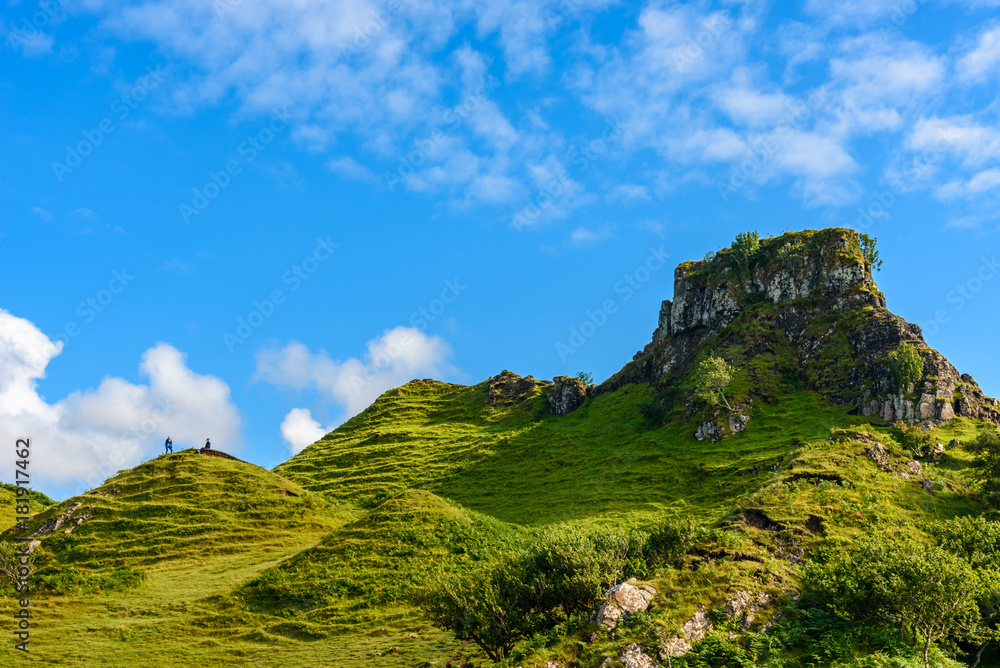 Tourist hiking the Mystic Fairy Glen, a romantic green valley in the Isle of Skye.
