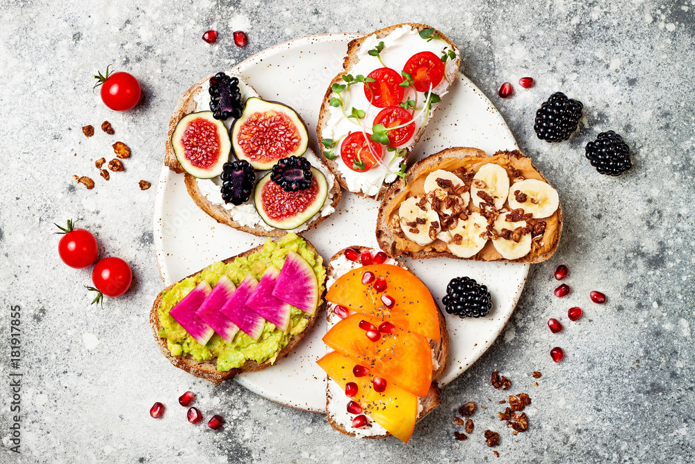 Healthy breakfast toasts with peanut butter, banana, chocolate granola, avocado, watermelon radish, persimmon, pomegranate, chia seeds, tomato, figs, blackberry. Healthy breakfast toasts with peanut butter, banana, chocolate granola, avocado, watermelon radish, persimmon, pomegranate, chia seeds, tomato, figs, blackberry.