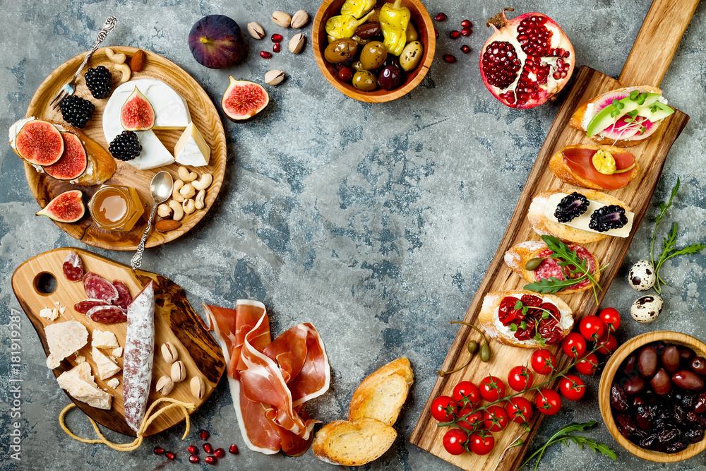 Appetizers table with italian antipasti snacks. Brushetta or authentic traditional spanish tapas set, cheese variety board over grey concrete background. Top view, flat lay, copy space Appetizers table with italian antipasti snacks. Brushetta or authentic traditional spanish tapas set, cheese variety board over grey concrete background. Top view, flat lay, copy space