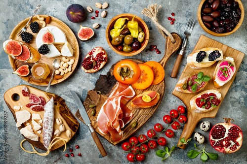Appetizers table with italian antipasti snacks. Brushetta or authentic traditional spanish tapas set, cheese variety board over grey concrete background. Top view, flat lay