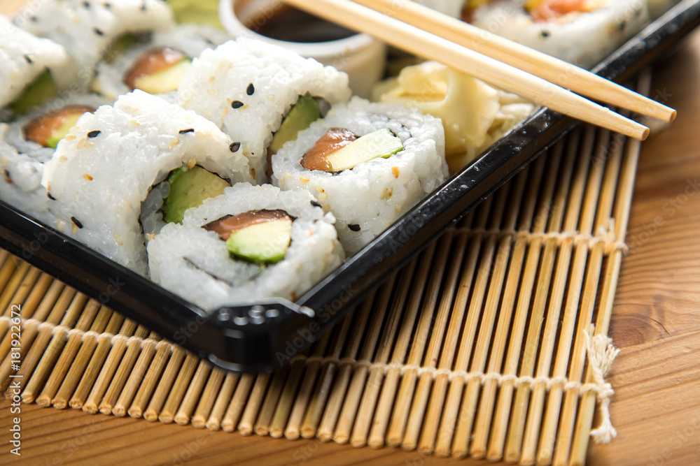 Lachs Avocado Inside Out Sushi in Lieferdienst Verpackung mit Stäbchen Lachs Avocado Inside Out Sushi in Lieferdienst Verpackung mit Stäbchen
