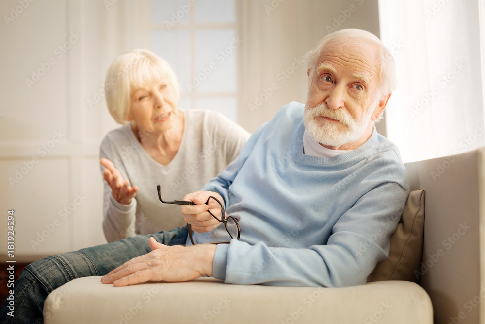 Want to think. Concentrated grey-haired man wrinkling forehead and looking forward while holding glasses in right hand Want to think. Concentrated grey-haired man wrinkling forehead and looking forward while holding glasses in right hand