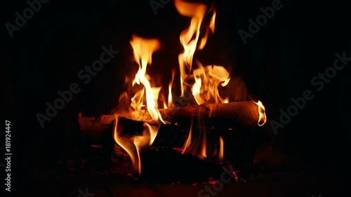 Logs burning in dark room in open fireplace in slow motion 96fps. Closeup on slowly burning logs in open indor fireplace.