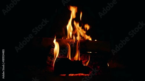 Arranging burning logs in open fireplace and lots of sparks comming out.