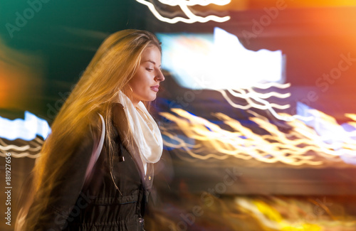 Woman in city at night among neon moving lights