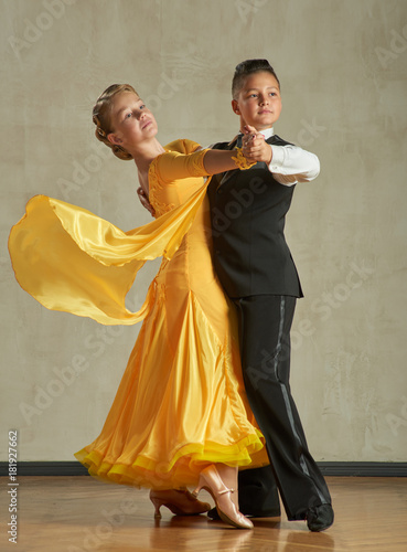Attractive young couple of children dancing ballroom dance in studio