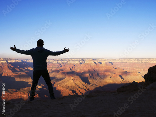 Man from the rear standing with outstretched arms overlooking th