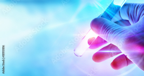 Hand of a scientist with test tube on blue background
