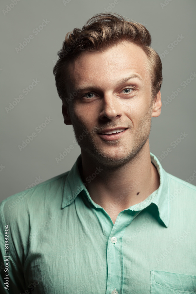 Male beauty, demon inside. Portrait of smiling 30-year-old man standing over gray background. Close up. Classic style. Wavy glossy blond hair. Studio shot Male beauty, demon inside. Portrait of smiling 30-year-old man standing over gray background. Close up. Classic style. Wavy glossy blond hair. Studio shot