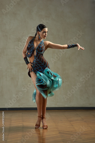 Attractive woman dancing ballroom dance in studio in gorgeous sexy latin costume