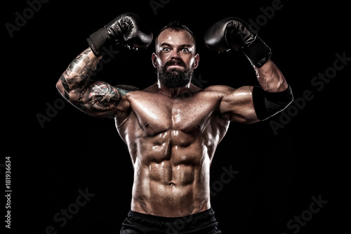 Boxer with tattoo in boxing gloves celebrating flawless victory. Sport concept isolated on black background.