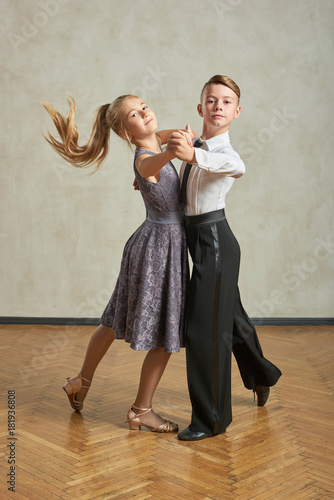 Fototapeta Attractive young couple of children dancing ballroom dance in studio