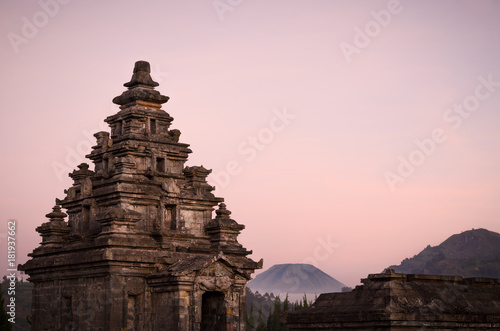 Sunset view of Dieng plateau with ancient stone hindu temple and volcano, in Java, Indonesia.