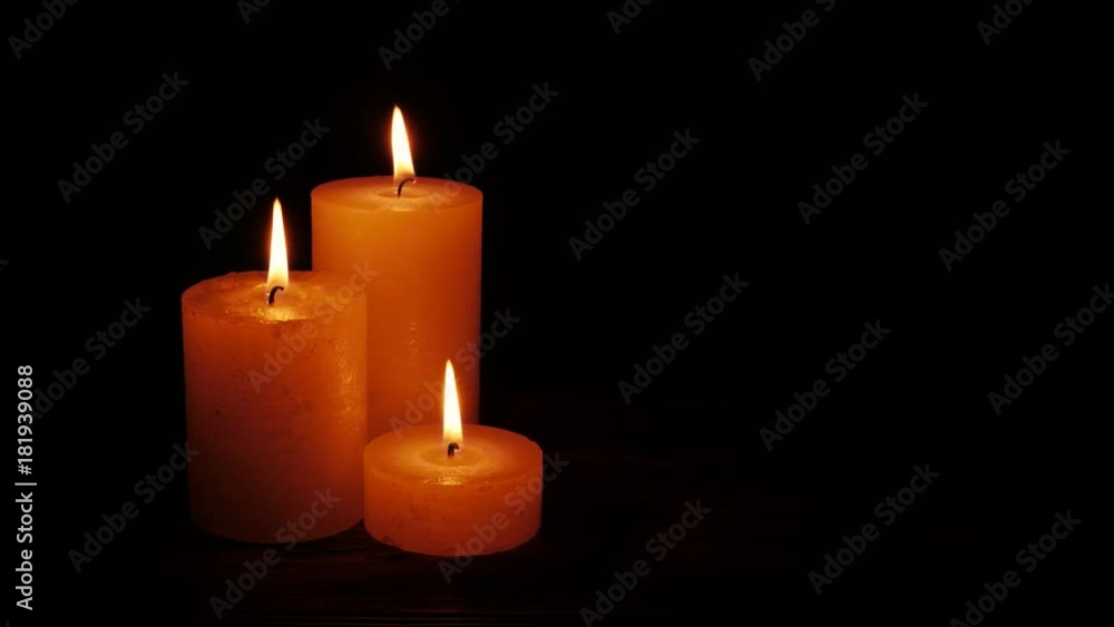 Warm candles gently burning in a black void. Candles group together on dark background Warm candles gently burning in a black void. Candles group together on dark background
