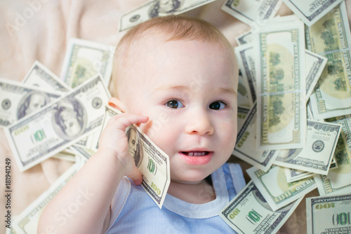 Cute baby boy playing with a lot of money like talking on telephone, american hundred dollars cash photo