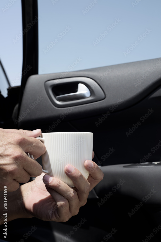 young man having a coffee in a car