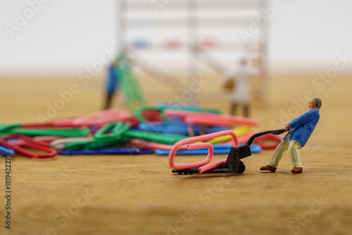 Miniature toy workers carry a paper clip