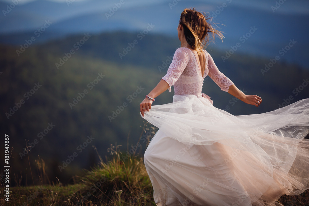 Bride whirls in her beautiful dress before stunning mountain landscape