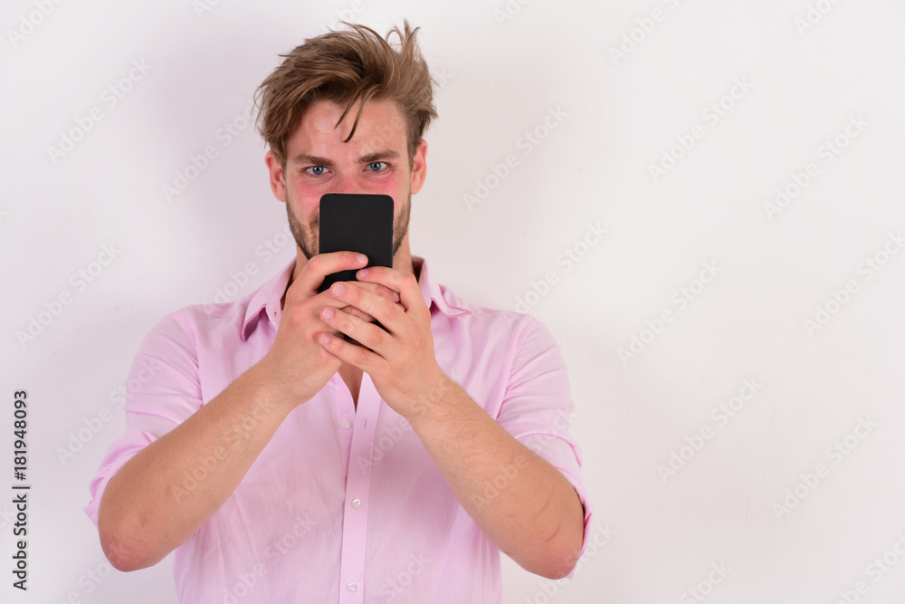 Man with stylish hair and curious face holds mobile phone. Man with stylish hair and curious face holds mobile phone.