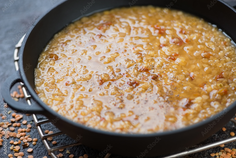 Close-up of a cast-iron pan with indian masoor dal or red lentils soup, selective focus, shallow depth of field