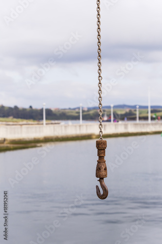 rusty hook and chain hanging in a small sea port
