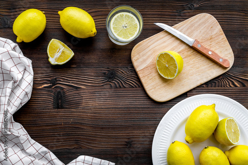 Cut lemons for lemonade. Lemons, glass, knife, cutting board on wooden background top view copyspace