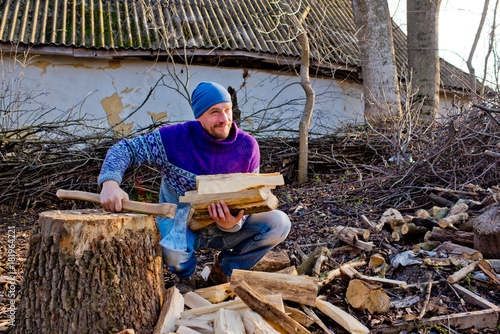 The woodcutter holds firewood in hand.