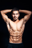 young handsome man with perfect torso on black background;