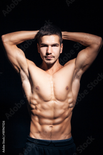 young handsome man with perfect torso on black background;