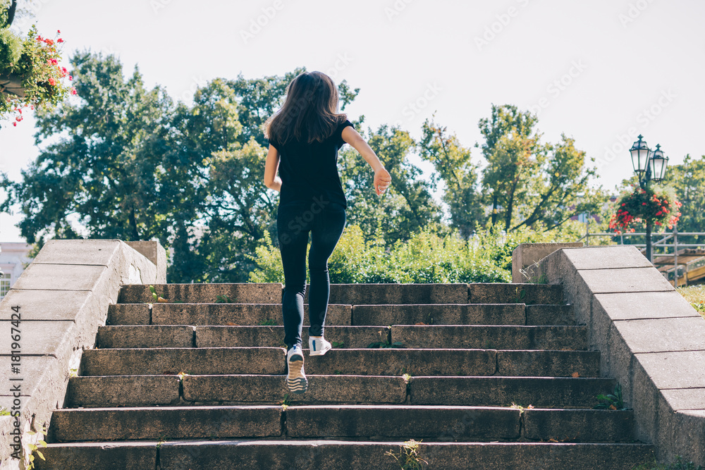 Woman in t-shirt and jeans runs up the stairs