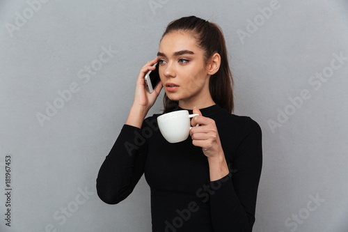 Young brunette woman in black clothes talking by smartphone photo