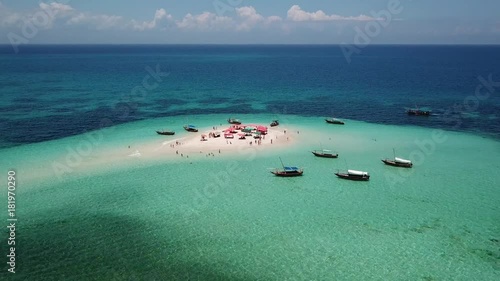 Aerial view of beautiful sand tropical island with white sand beach and tourists. White sand island. Seascape: ocean and beautiful beach paradise. Zanzibar, Tanzania. 4K video. Travel concept
