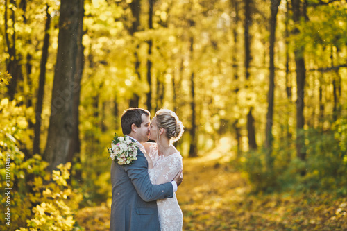 Embrace of the newlyweds on background of Sunny autumn forest 25. © alenazamotaeva