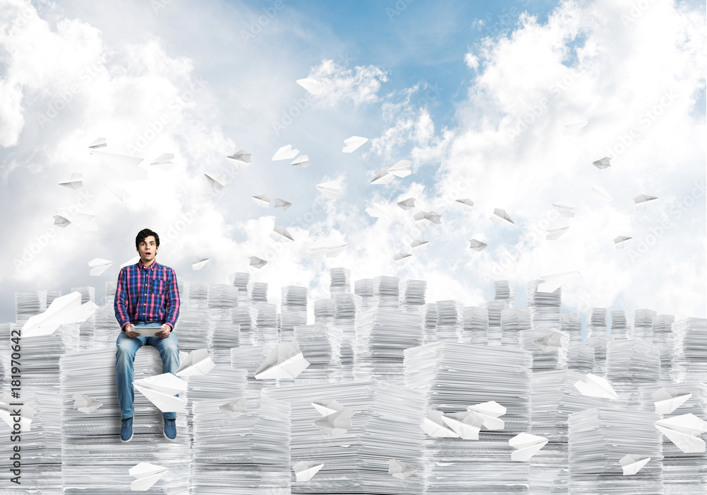 Attractive man sitting on pile of paper documents. Attractive man sitting on pile of paper documents.