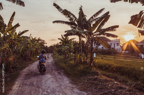 Scooter driving in Bali during epic sunset: vintage style.