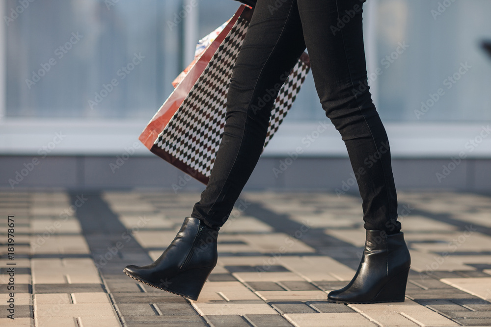 Sexy woman legs in black platform shoes and black jeans with Shopping Bags  walking in the city urban street. Steadicam stabilized shot in Slow motion.  Stock Photo | Adobe Stock