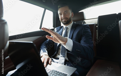 businessman sitting in the back seat in the car and pointing his finger forward © ASDF