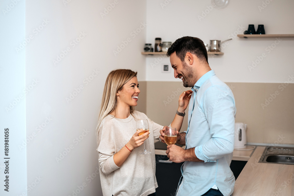 Fototapeta premium Shot of couple in kitchen drinking wine and talking.