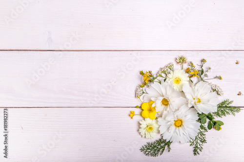 A bouquet of white cosmea or cosmos on white boards. Garden yellow flowers over handmade wooden table background. Backdrop with copy space. Mother s  Valentines  Women s  Wedding Day concept.