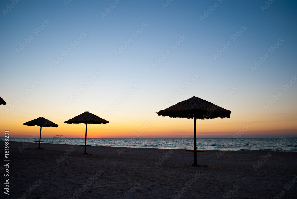 several a lot of big beach umbrellas made of straw and metal stand on the beach sand beach blue sea blue sky summer morning evening calm